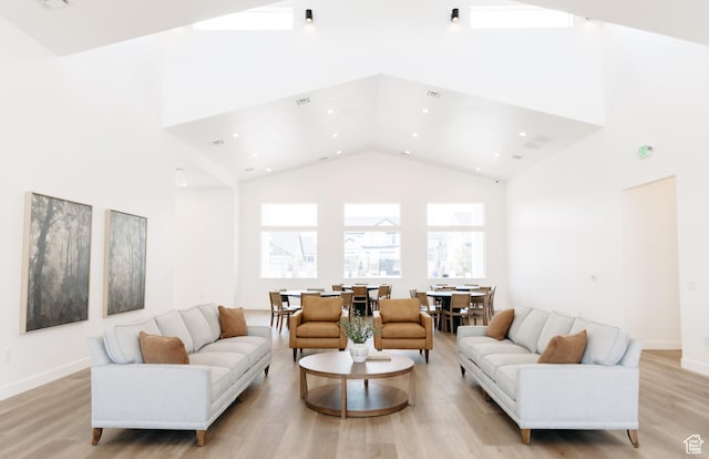 living room with high vaulted ceiling, light wood-style floors, recessed lighting, and baseboards