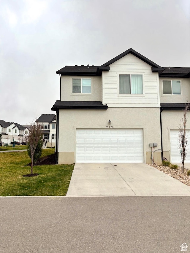 view of front of house featuring a garage, driveway, stucco siding, and a front lawn