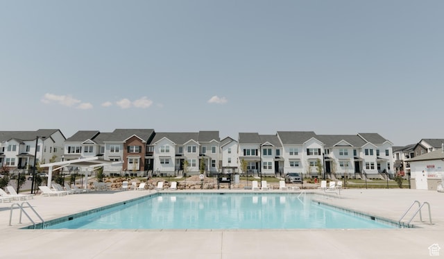 community pool featuring a residential view, fence, and a patio area
