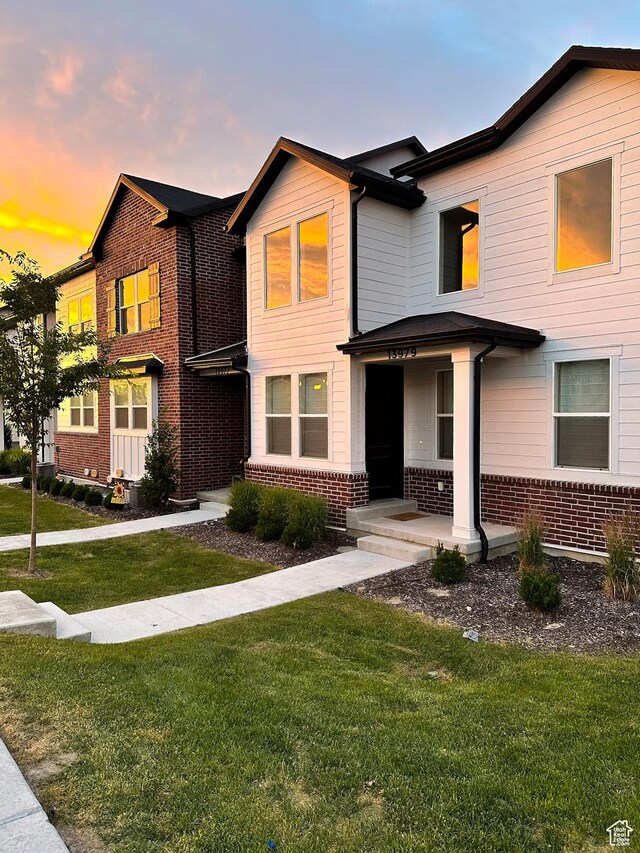 view of front of home with brick siding and a lawn