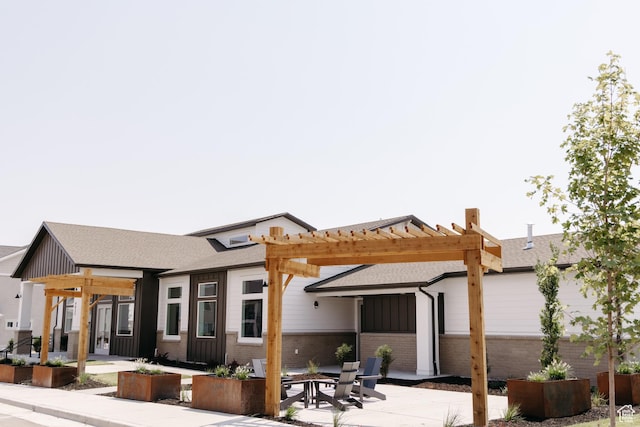 rear view of house featuring a pergola, a patio area, a shingled roof, a fire pit, and brick siding