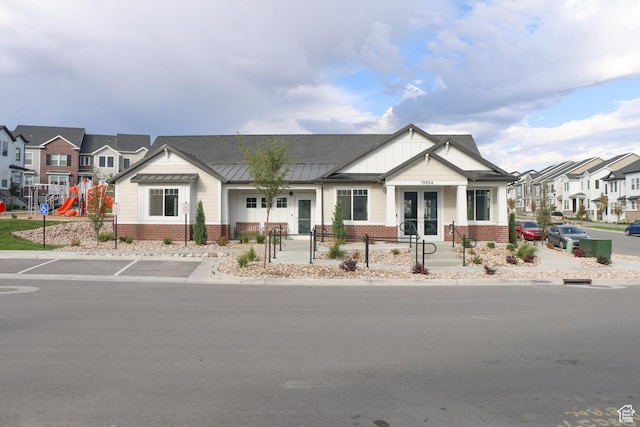 view of front of home featuring french doors, brick siding, a standing seam roof, a residential view, and uncovered parking