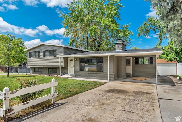 tri-level home featuring driveway, a chimney, brick siding, a porch, and a carport
