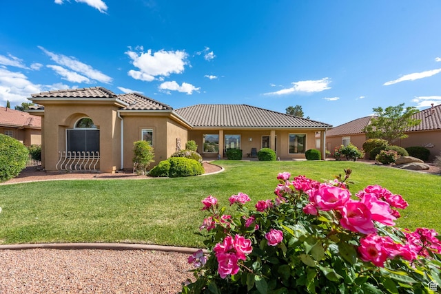 rear view of property featuring a tiled roof, stucco siding, and a yard