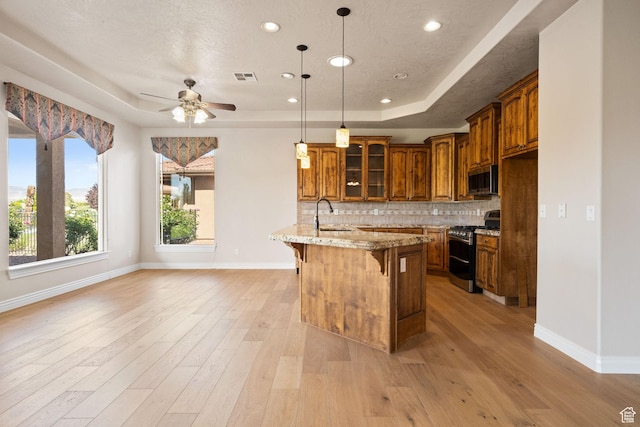 kitchen featuring stainless steel appliances, a raised ceiling, a kitchen breakfast bar, brown cabinets, and recessed lighting