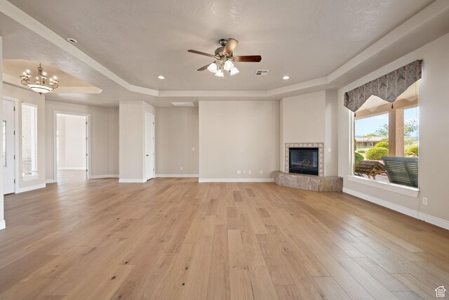 unfurnished living room with a raised ceiling, light wood-style flooring, a tiled fireplace, and recessed lighting