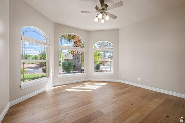 spare room with ceiling fan, baseboards, and light wood-style flooring