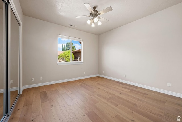 unfurnished bedroom featuring light wood-style flooring, baseboards, a closet, and a ceiling fan