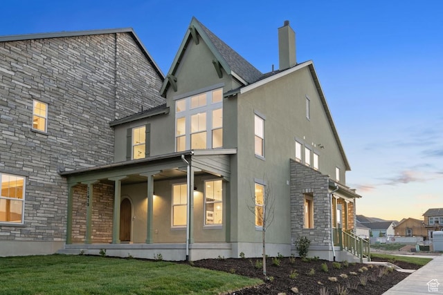 11419 S Watercourse Rd Unit 188, South Jordan, UT 84009 - back of property featuring stone siding, stucco siding, a lawn, and a chimney