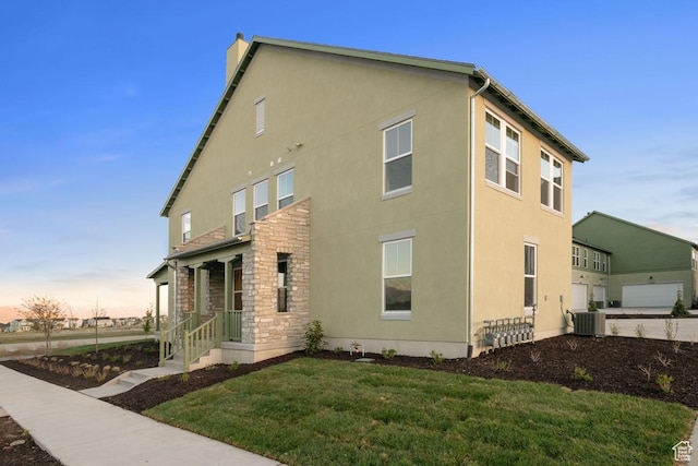 11419 S Watercourse Rd Unit 188, South Jordan, UT 84009 - view of property exterior with stucco siding, a yard, a chimney, central air condition unit, and stone siding