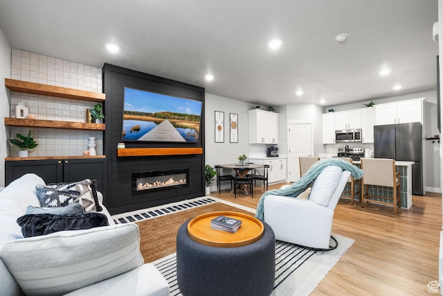 living room with a fireplace, light wood-style floors, and recessed lighting