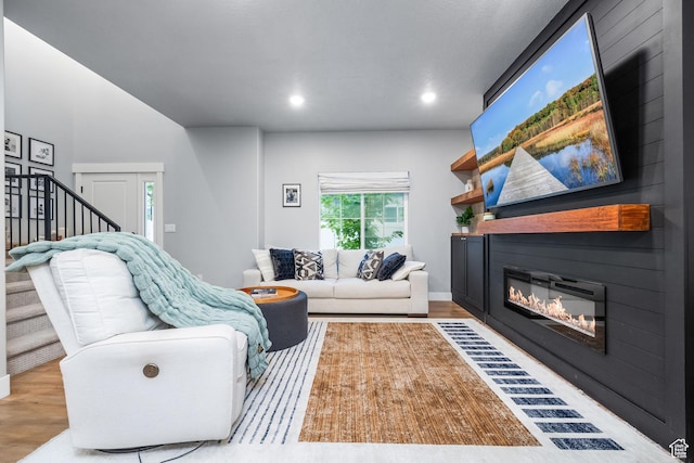living room featuring a large fireplace, wood finished floors, stairway, and recessed lighting