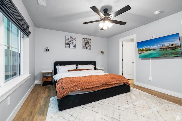 bedroom featuring wood finished floors, baseboards, and ceiling fan