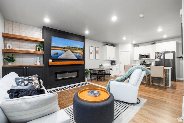 living area with light wood finished floors, recessed lighting, and a large fireplace