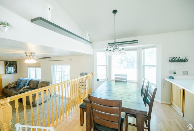 dining area featuring light wood-style floors, a chandelier, a ceiling fan, and high vaulted ceiling