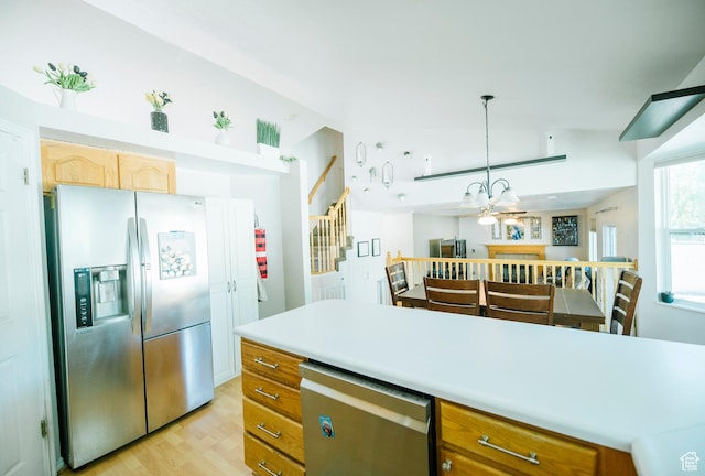 kitchen with stainless steel appliances, light wood finished floors, light countertops, decorative light fixtures, and a chandelier