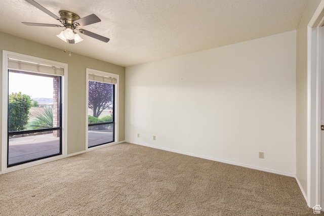 empty room featuring carpet flooring, a textured ceiling, baseboards, and a ceiling fan
