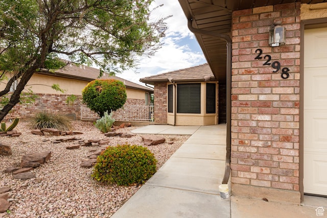 doorway to property featuring brick siding and fence