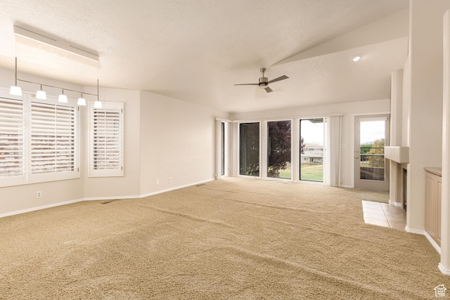 empty room featuring carpet flooring, ceiling fan, baseboards, lofted ceiling, and a fireplace with flush hearth