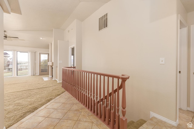 hall featuring an upstairs landing, light carpet, light tile patterned flooring, vaulted ceiling, and baseboards