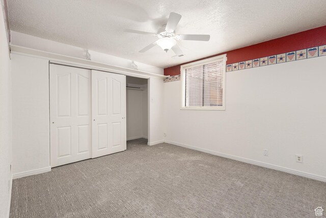unfurnished bedroom featuring carpet, a closet, a textured ceiling, ceiling fan, and baseboards