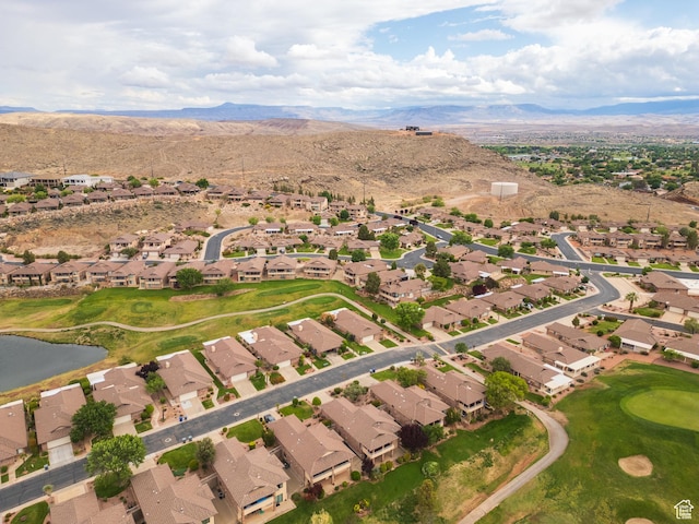 aerial view of property and surrounding area featuring nearby suburban area, a golf course, and a water and mountain view