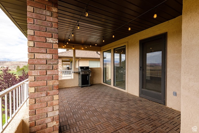 view of patio featuring area for grilling, a balcony, and exterior kitchen
