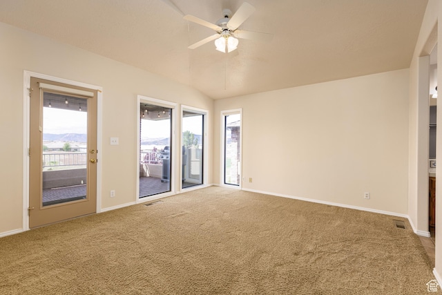 carpeted empty room with ceiling fan, vaulted ceiling, and baseboards
