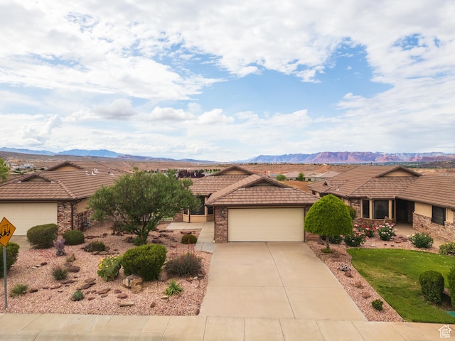 view of front facade featuring a tiled roof, a garage, concrete driveway, and a mountain view