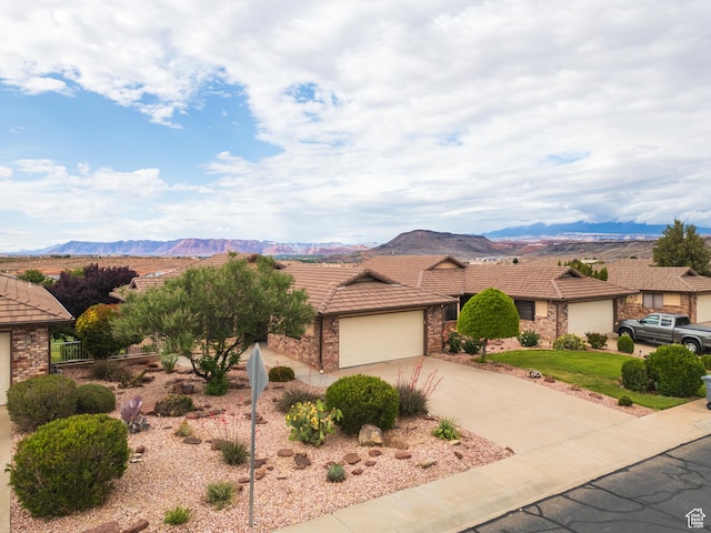 view of front facade with a tiled roof, driveway, a mountain view, and an attached garage