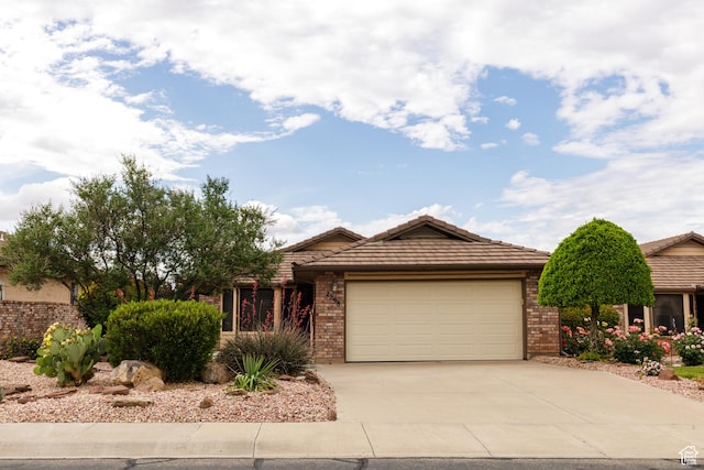 view of front facade featuring a garage, driveway, brick siding, and a tile roof