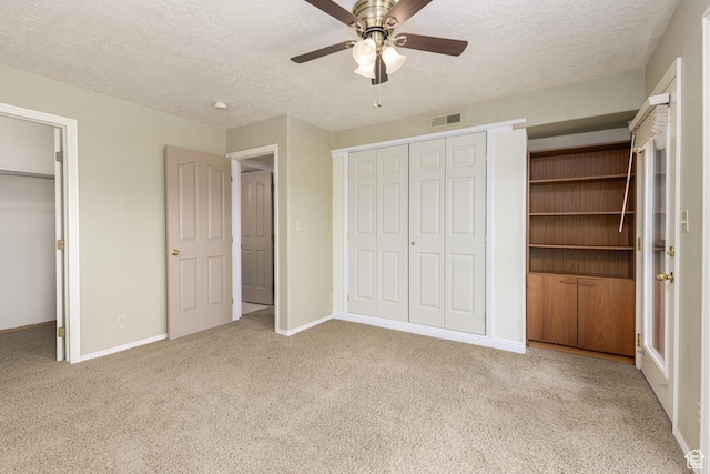 unfurnished bedroom featuring carpet flooring, a textured ceiling, baseboards, and ceiling fan
