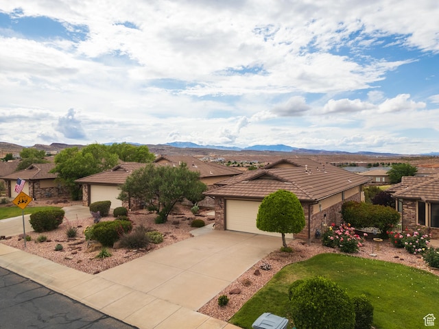 single story home featuring a tiled roof, concrete driveway, a mountain view, and a residential view