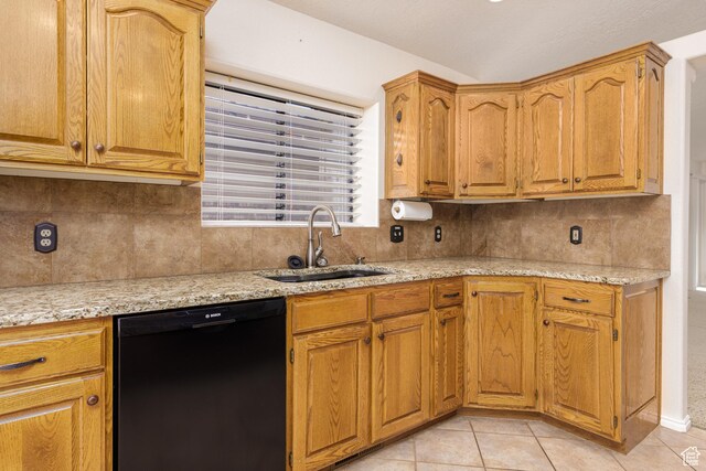 kitchen featuring black dishwasher, a sink, tasteful backsplash, and light tile patterned floors