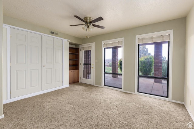 unfurnished bedroom with access to outside, carpet, baseboards, a textured ceiling, and ceiling fan