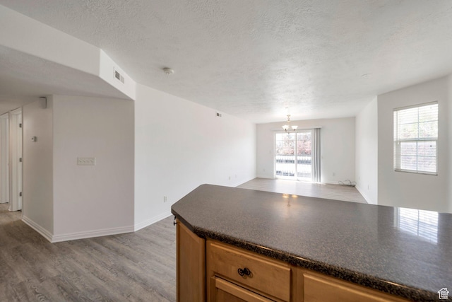 14034 S Sonora Way, Bluffdale, UT 84065 - kitchen with dark countertops, light wood-style floors, a textured ceiling, a chandelier, and open floor plan