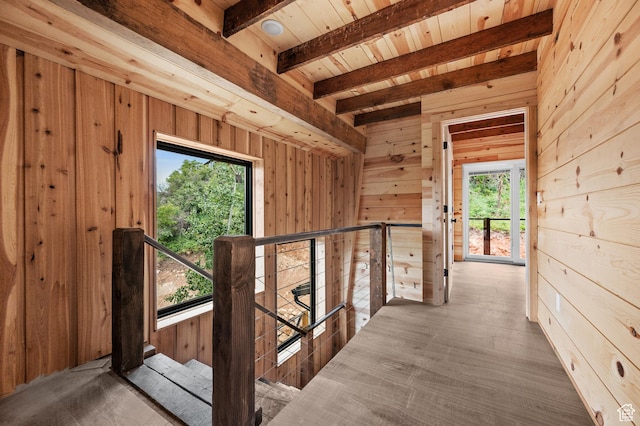 hallway featuring an upstairs landing, wooden walls, beam ceiling, wood ceiling, and wood finished floors