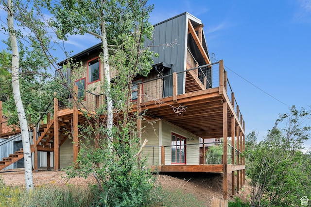 rear view of house featuring stairs and a wooden deck