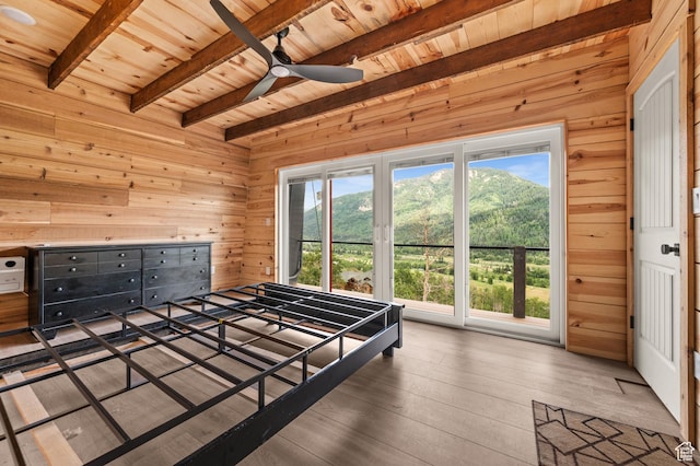 bedroom with wood ceiling, wood walls, beamed ceiling, multiple windows, and hardwood / wood-style flooring