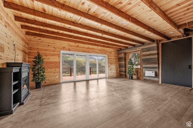 unfurnished living room with beamed ceiling, wood ceiling, wooden walls, light wood-style flooring, and a glass covered fireplace