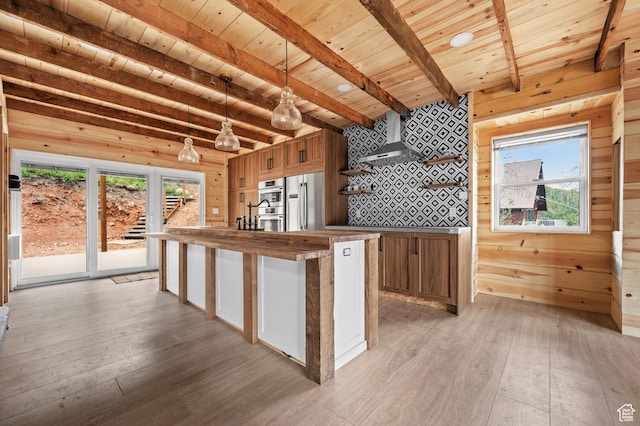 kitchen with stainless steel refrigerator, light wood finished floors, wood ceiling, beamed ceiling, and wall chimney exhaust hood