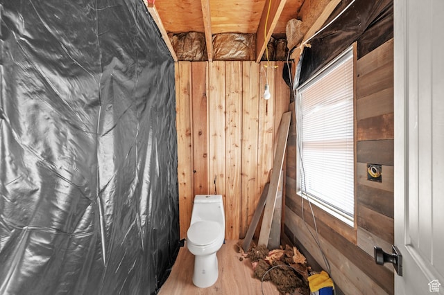 bathroom with wooden walls, toilet, and wood finished floors