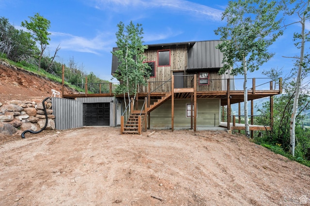 view of front of house featuring dirt driveway, stairway, a deck, and a garage