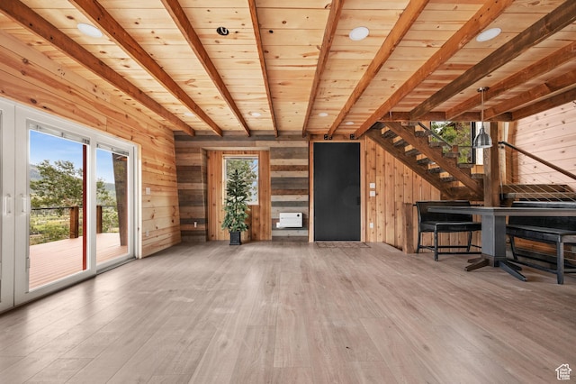 unfurnished living room featuring wood walls, wood-type flooring, beamed ceiling, stairway, and wood ceiling