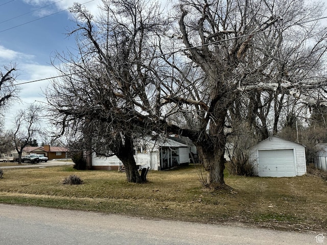 view of front of home featuring an outdoor structure, a detached garage, and a front yard