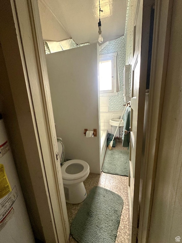 full bath with toilet, water heater, and a bath