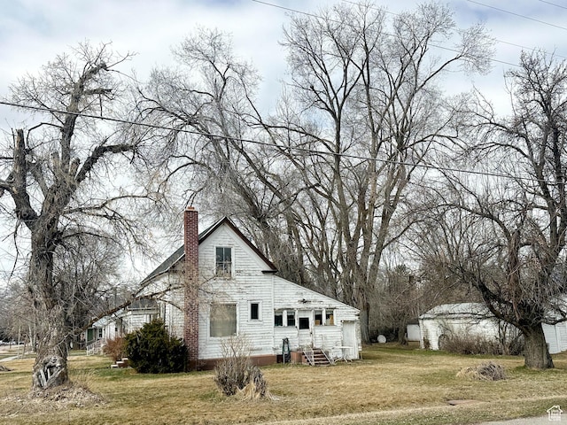 view of side of home with a chimney, entry steps, and a yard
