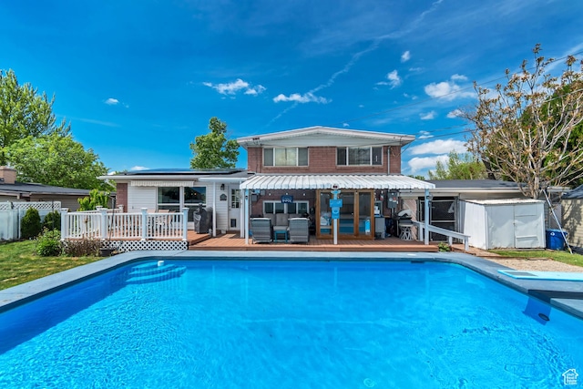 view of pool with a deck, an outbuilding, a storage unit, and fence