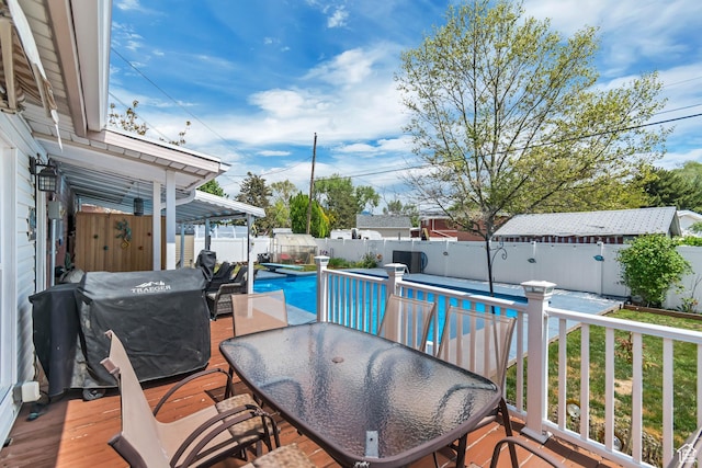 wooden terrace with a fenced backyard, outdoor dining area, and grilling area