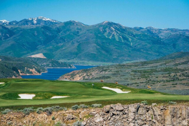 view of mountain backdrop featuring a golf course and a nearby body of water